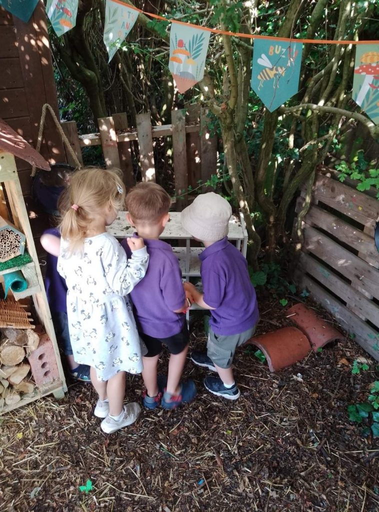 3 children gathered around the bug house