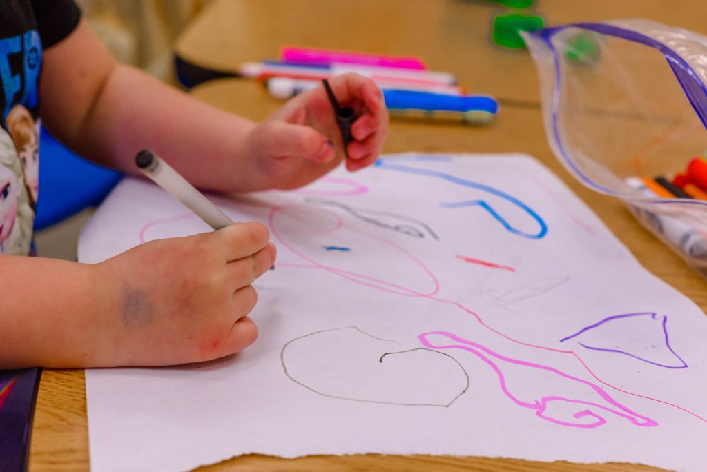 Children drawing with pens on white paper