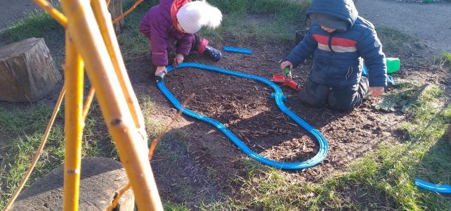 Children playing with a race track outside