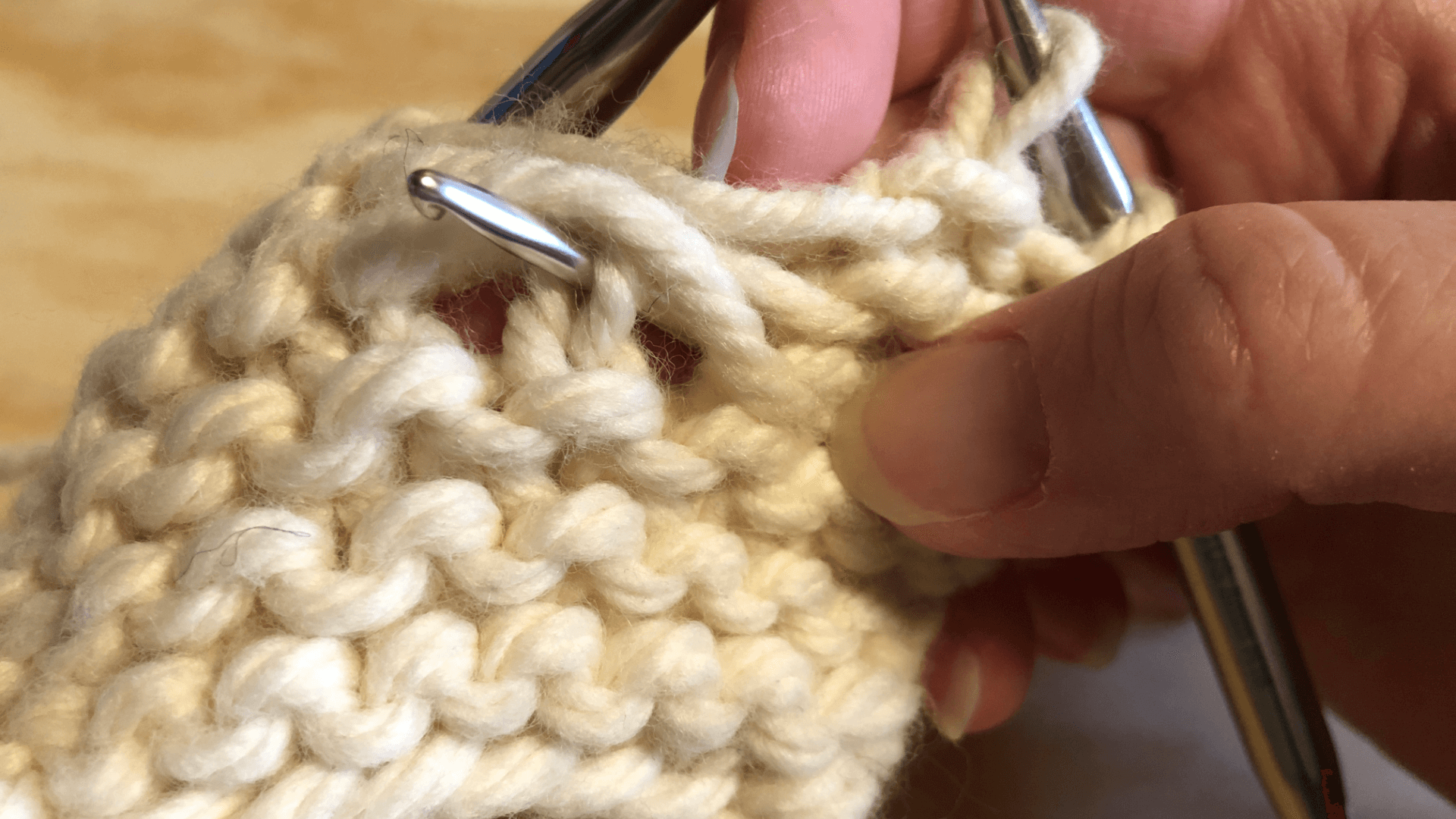 Showing how to insert the crochet hook from the back when rescuing dropped purl stitches.