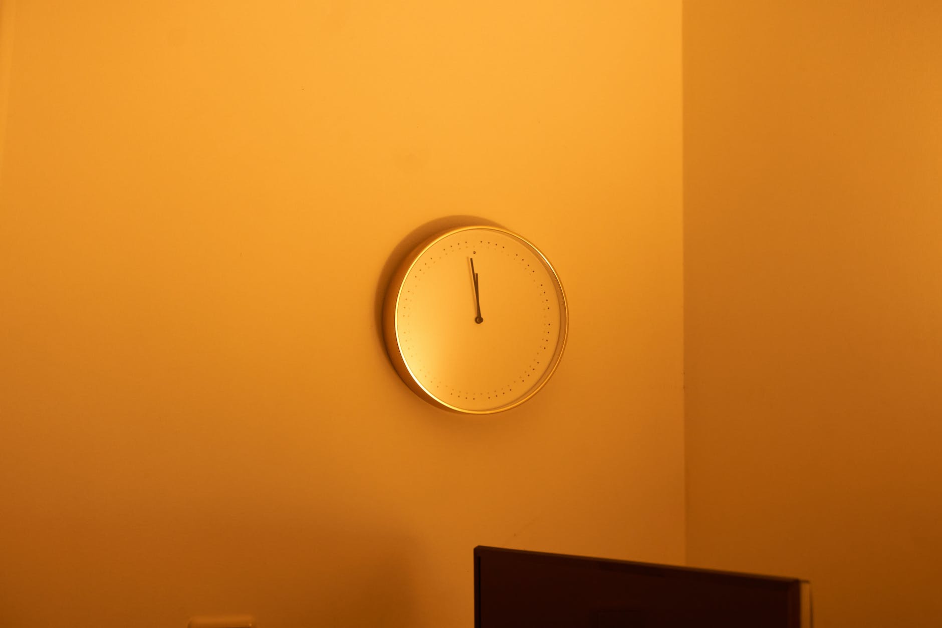 photo of an analog clock on an orange wall