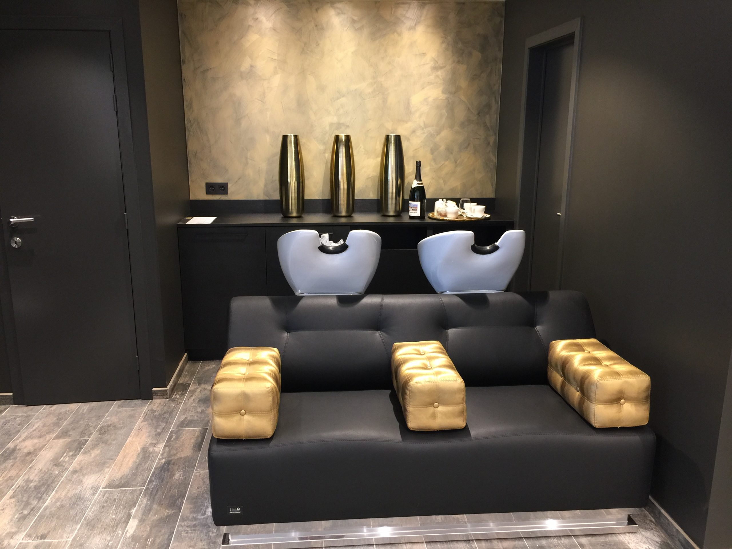 Luxe wasruimte in kapsalon met moderne wasstoelen, donkere tinten en stijlvolle gouden accenten.