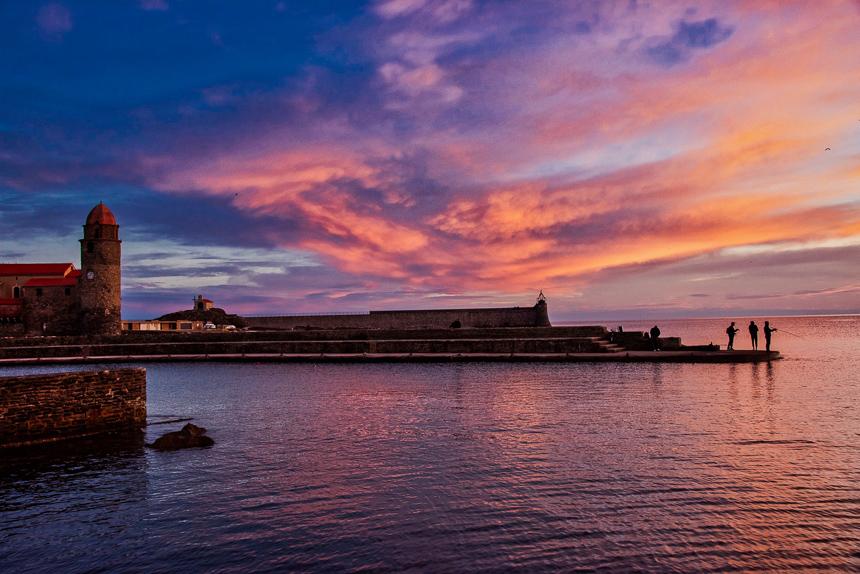 Sunrise over Collioure and hopeful fishermen. The landmark church of Our Lady of the Angels is on the left.