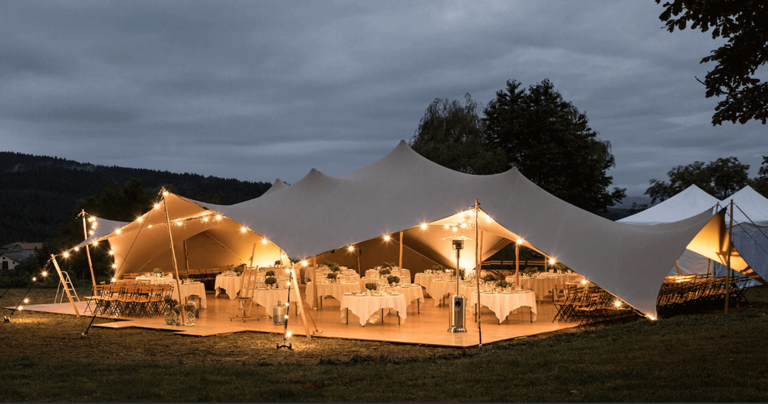 Stretch tent fully lit up at dusk before an evening wedding party