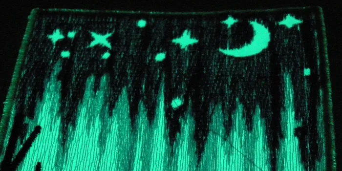 Inzoomat på fluorescerande broderad patch som lyser i mörkret.