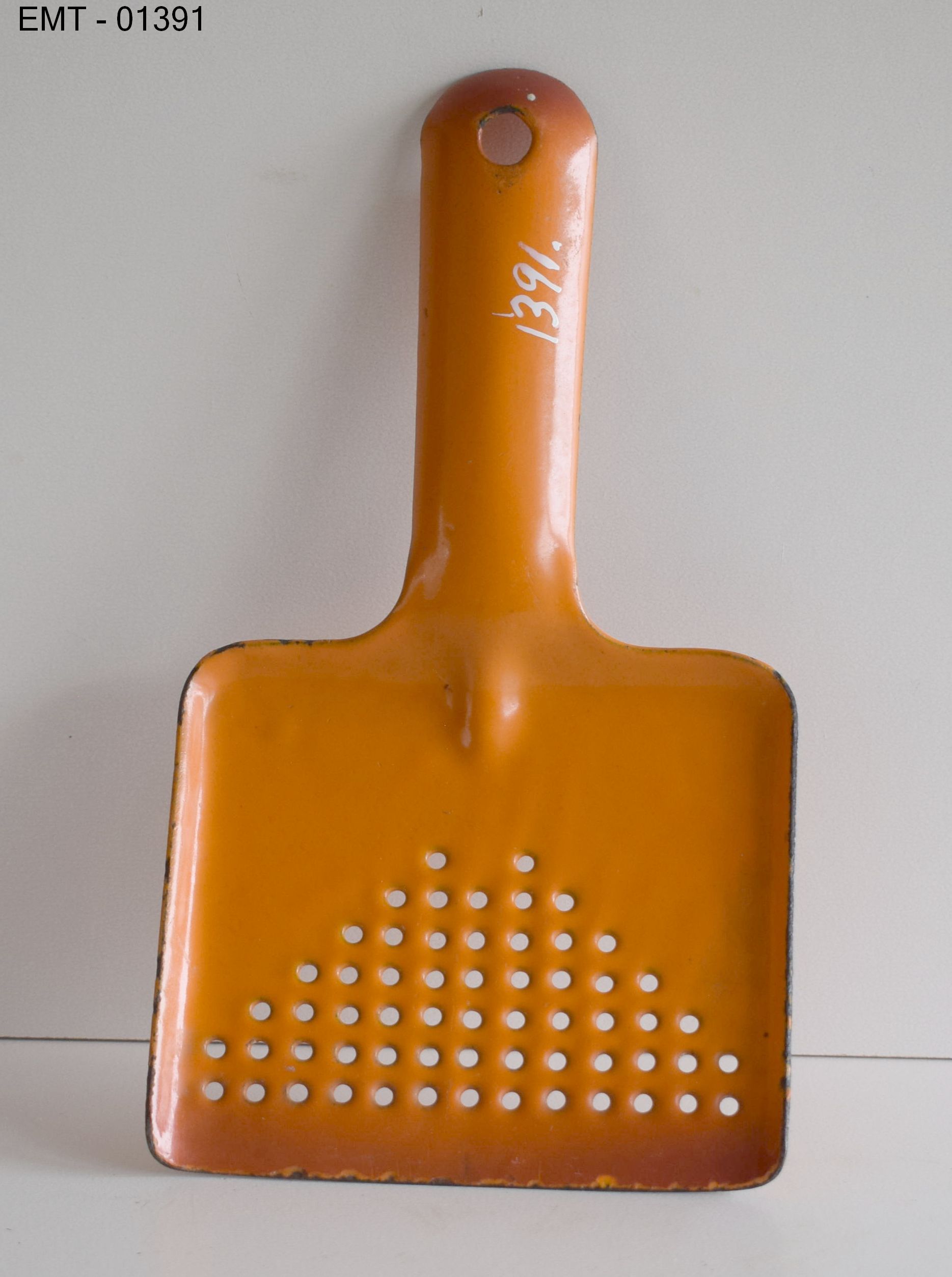 Skidtskraber. 2x21x0,5 cm. Emaljeret ”skovl” med håndtag, skovlen forsynet med mange huller farve orange. Til opsamling af snavs i gamle jernvaske.<br />
