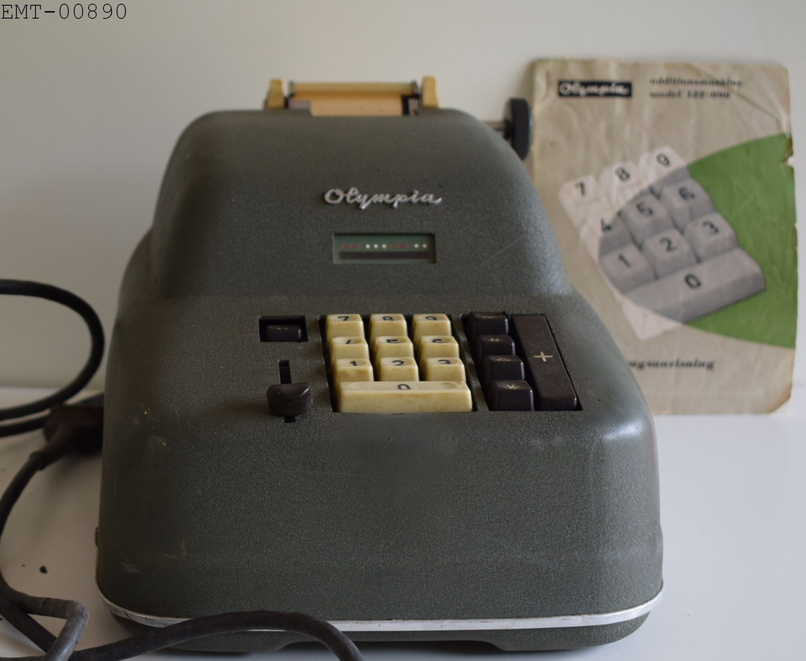 Regnemaskine; elektrisk 30x22x19 cm. Elektrisk regnemaskine med papirstrimmel mrk. Olympia. Anvendt af giverens mand K.M. Christensen som førte regnskab bl.a. for egnens landmænd brug ophørte ca. 1970-75 da nyere modeller eklektisk fremkom. 