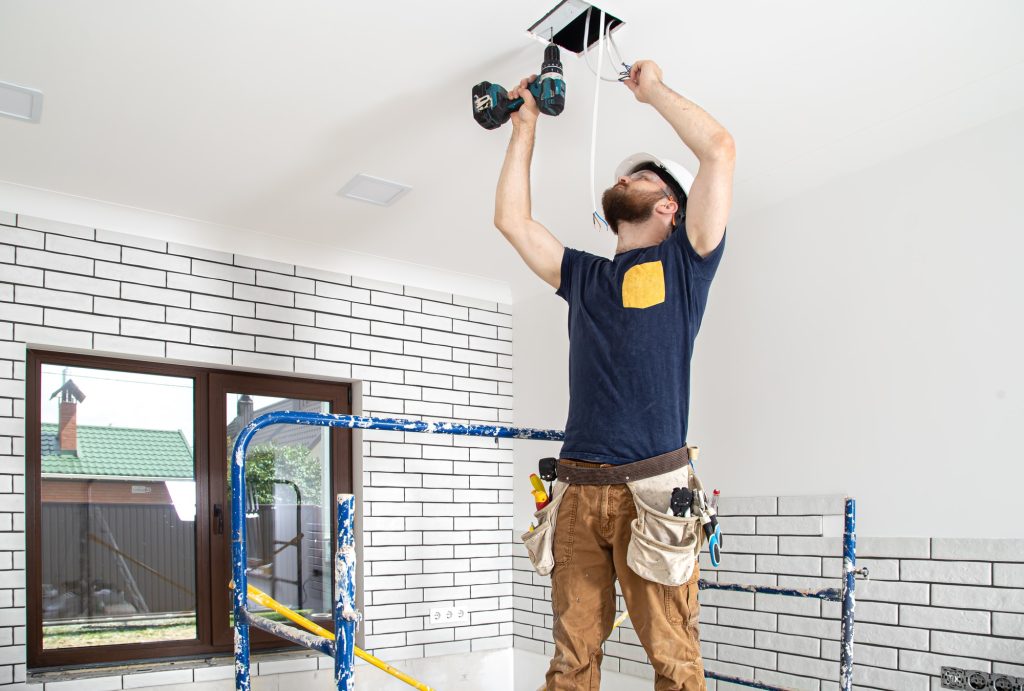 Electrician Builder at work, installation of lamps at height.