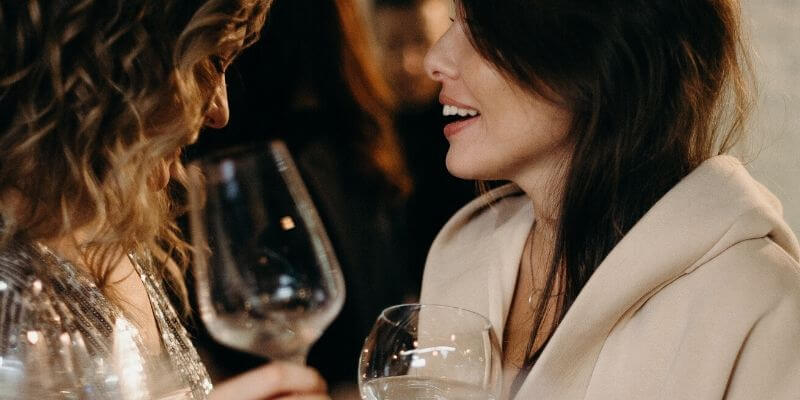 due ragazze con bicchiere di vino in mano chiacchierano