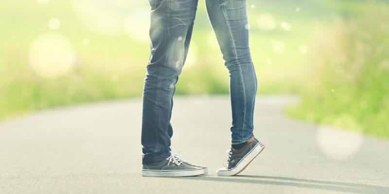 i piedi di due ragazzi in jeans e scarpe da ginnastica