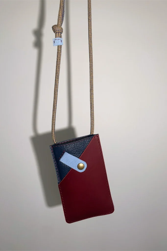 Blauw smartphonetasje met bordeaux zakje voor bankkaarten. Tasje uit de Phone Cord Series van Elise Verdegem.