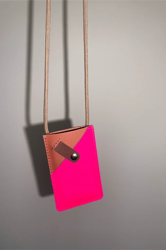 Roze leren smartphonetasje uit The Cord Series van Elise Verdegem. The Phone Cord in roze en fluoroze is gemaakt in België.