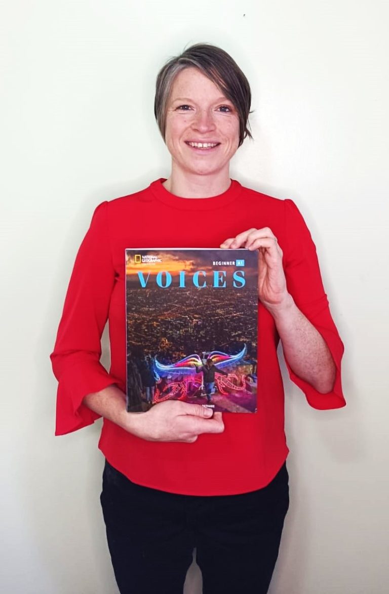 Emily Bryson ELT holding a copy of one of her books. The book is Voices Beginner, published by National Geographic Learning (Cengage).