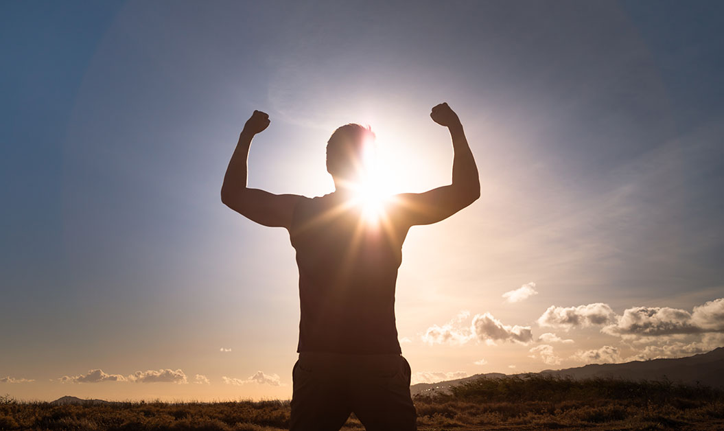 Persoon die tegen de zon instaat in een kracht pose