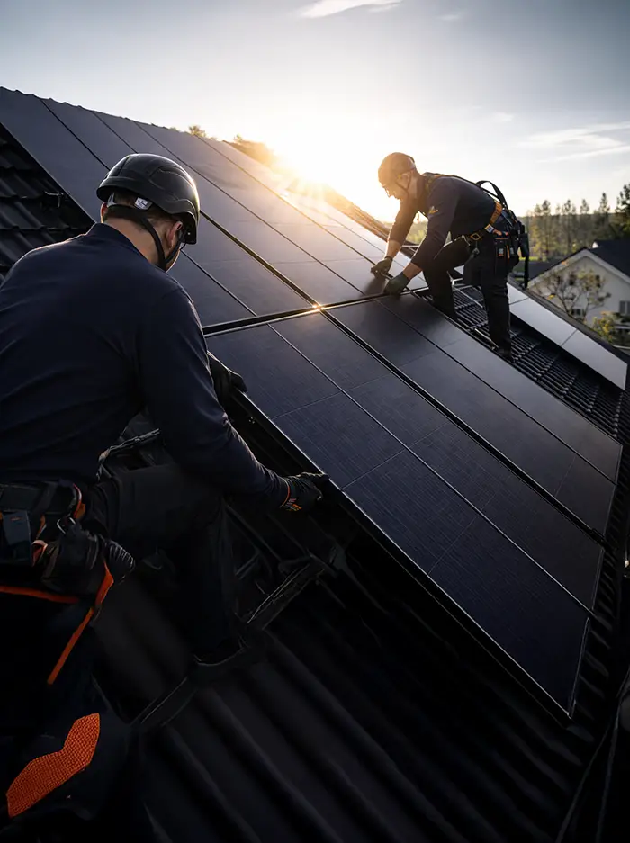 två installatörer som installerar solceller på villatak