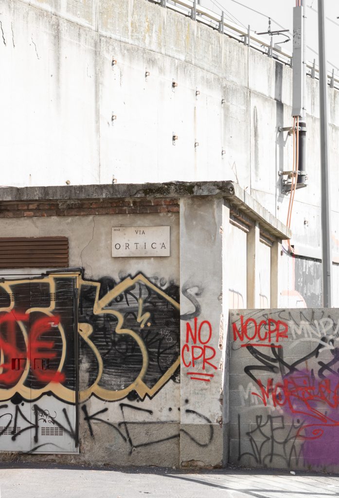 Muro in cemento con graffiti in Via Ortica, Milano.  La scritta è nera e oro- Foto di Marta Roncalli