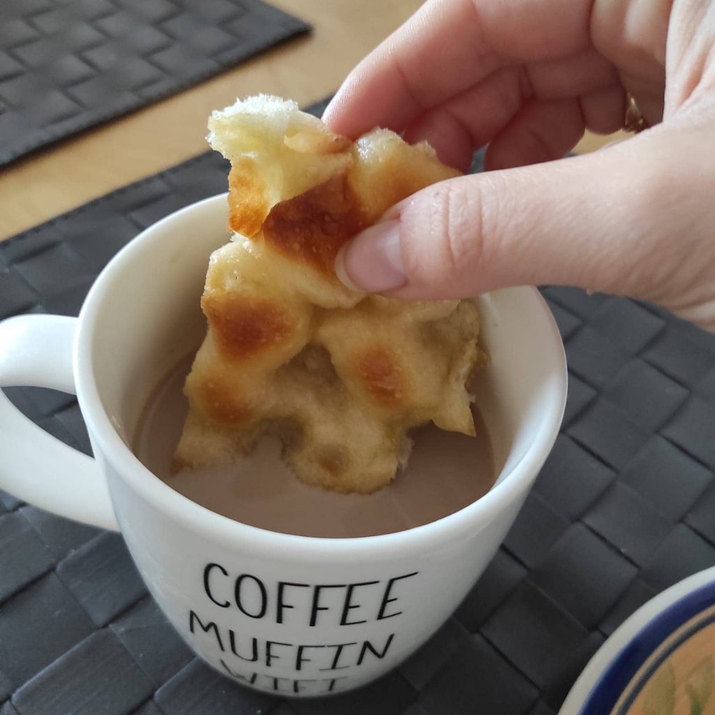 Focaccia genovese inzuppata nel caffè latte durante la colazione ligure