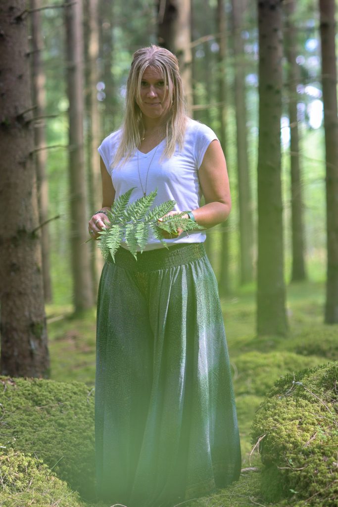 Kvinna tittar in i kameran i skogen