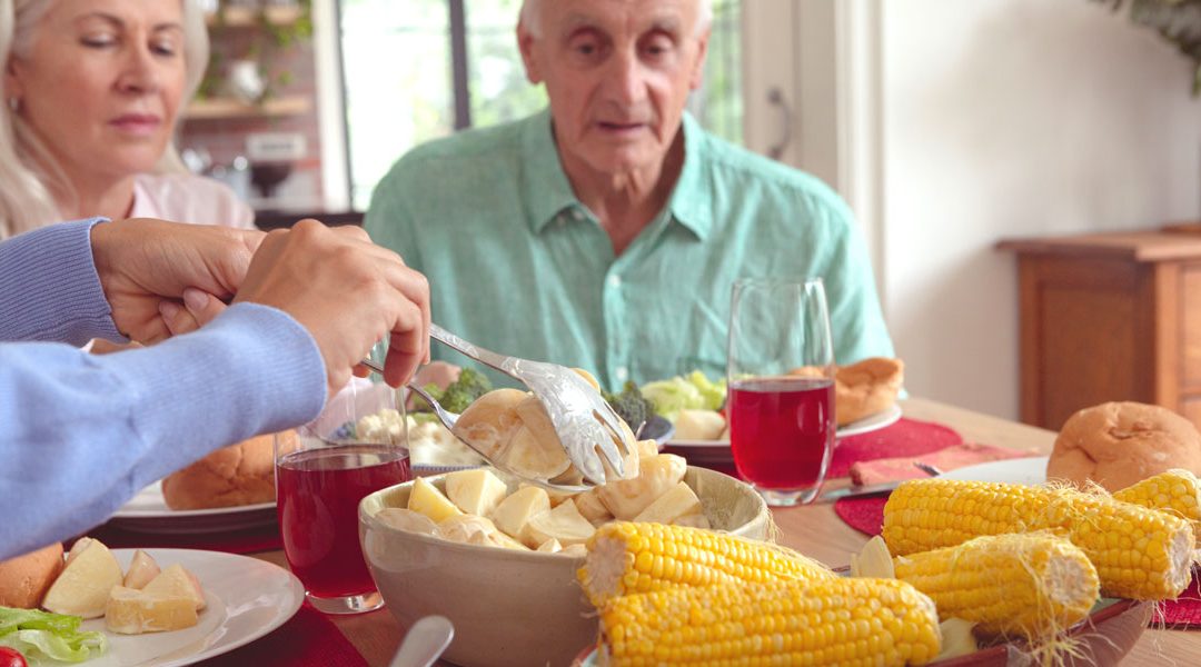 Man and woman at dinner table eating corn and vegetables