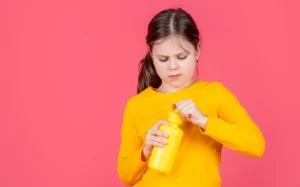 kid-hold-water-bottle-pink-background