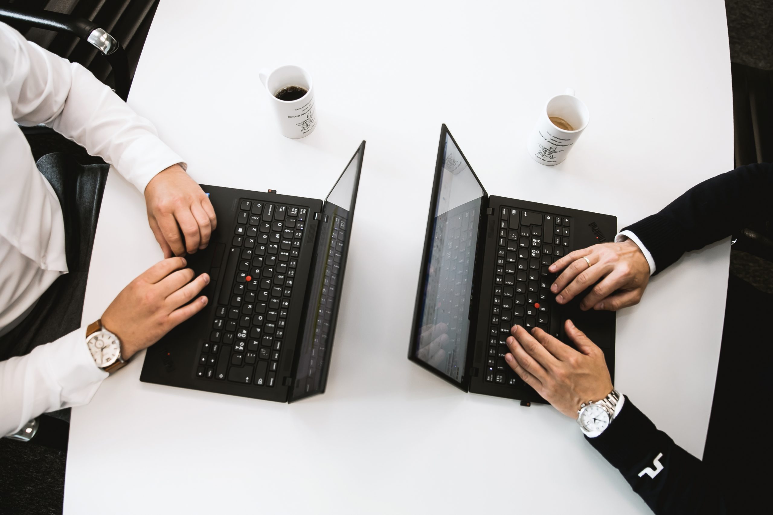 To personer som jobber på PC og drikker kaffe