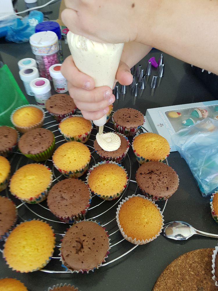 vanille en chocolade cupcakes en de spuitzak gevuld met botercrème