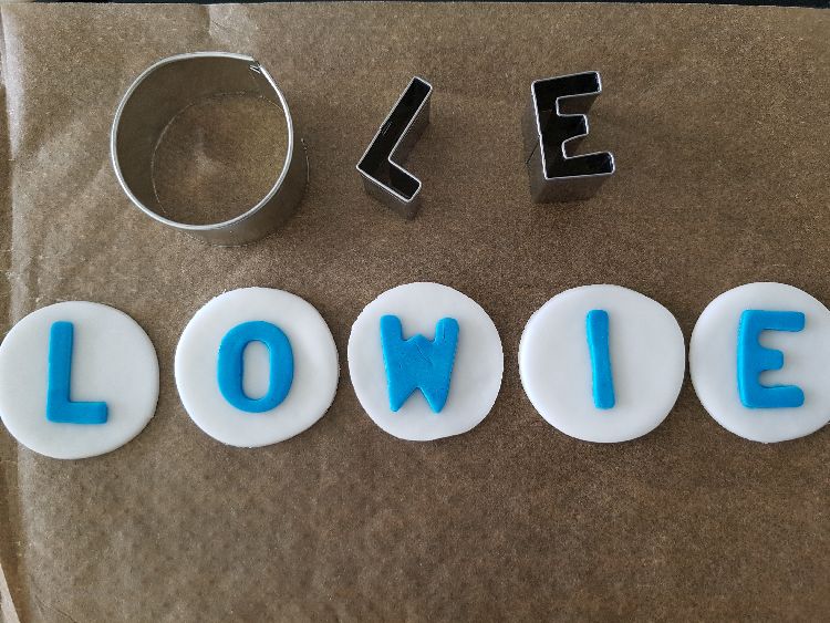 belettering in blauwe rolfondant en witte ronde rolfondant als achtergrond