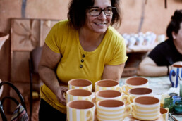 woman moving hand painted coffee cups in a pottery studio in Corval in portugal