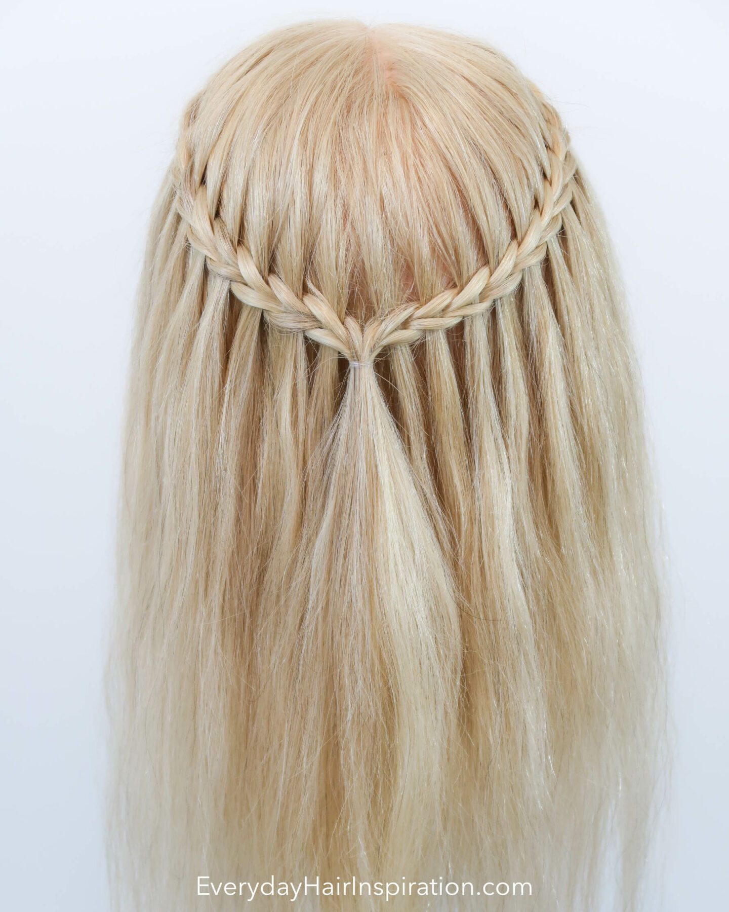 Blonde hairdresser head with a half up half down hair styles with a scissor waterfall braid, seen from the back. 