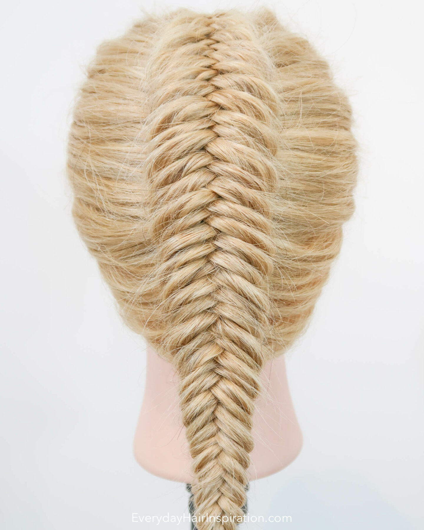 Blonde hairdresser doll seen from the back, with a single dutch fishtail braid in the hair