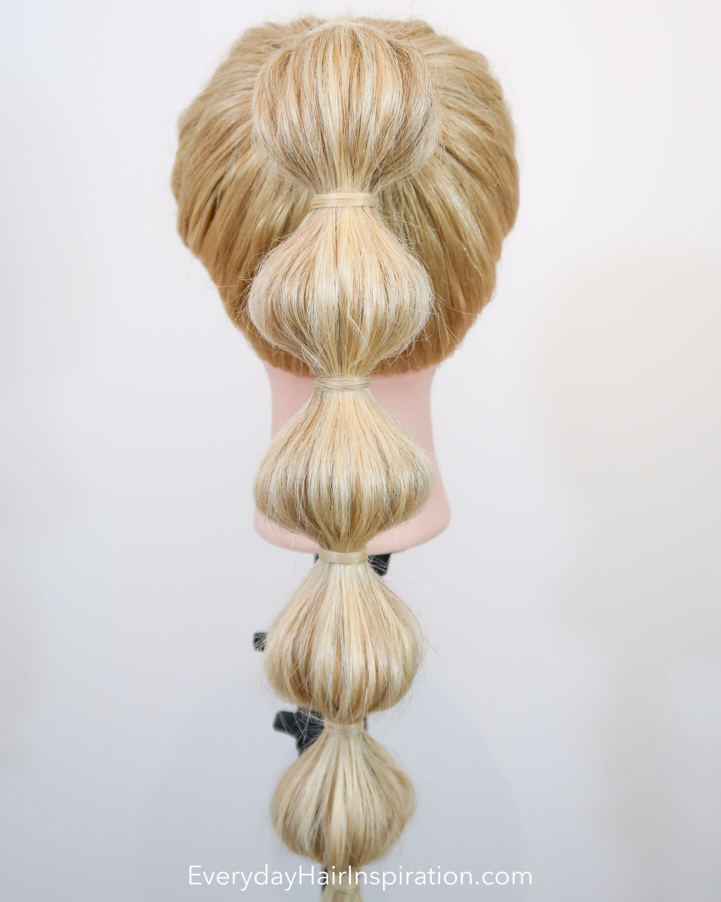 Blonde hairdresser doll, seen from the back with a high ponytail with a bubble braid down the hair. 