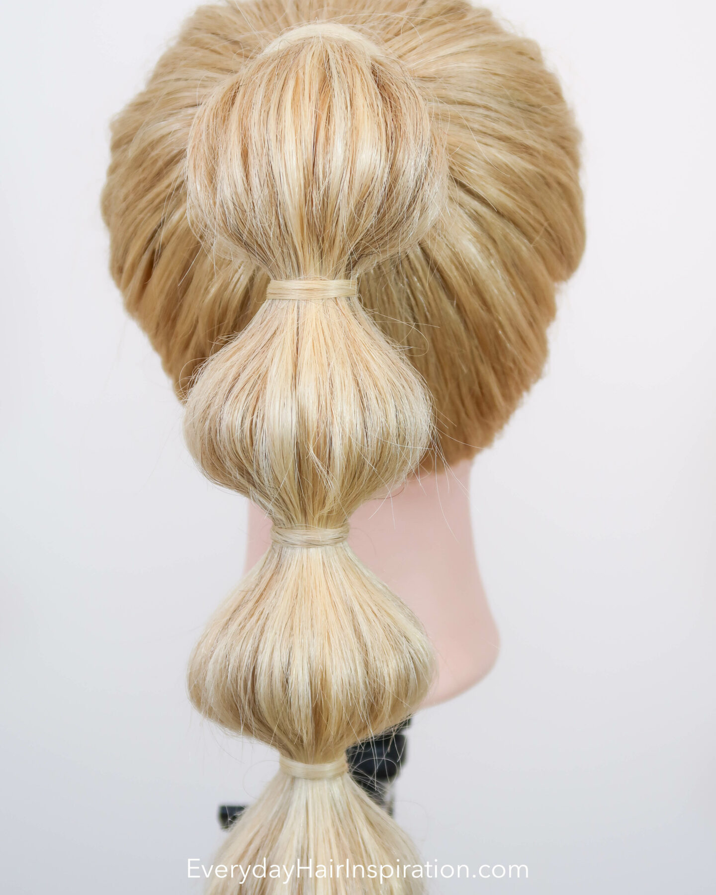 Blonde hairdresser doll, seen from the back with a high ponytail with a bubble braid down the hair. Closeup. 