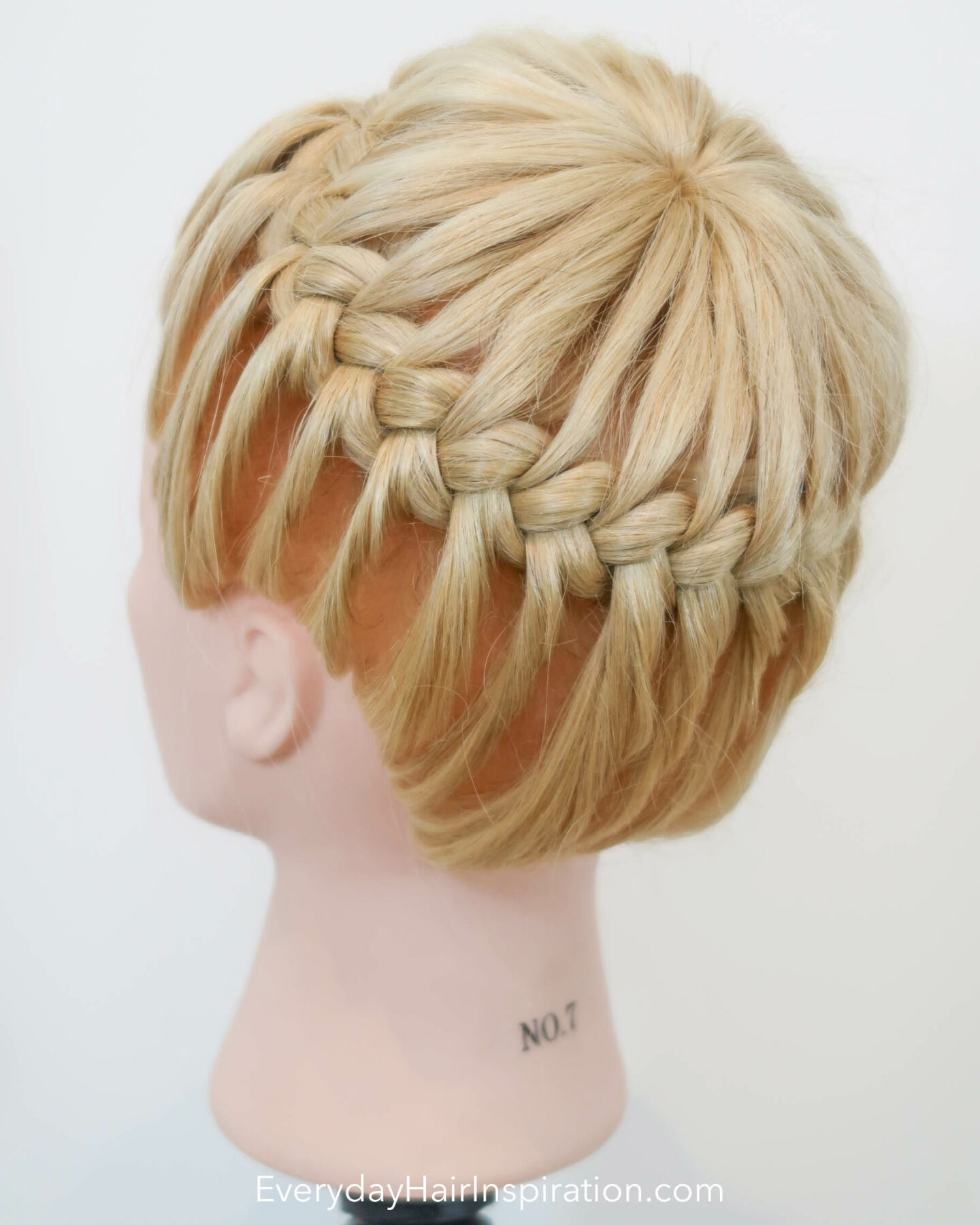 Blonde hairdresser doll seen from the side with a crown braid, braided in the hair.