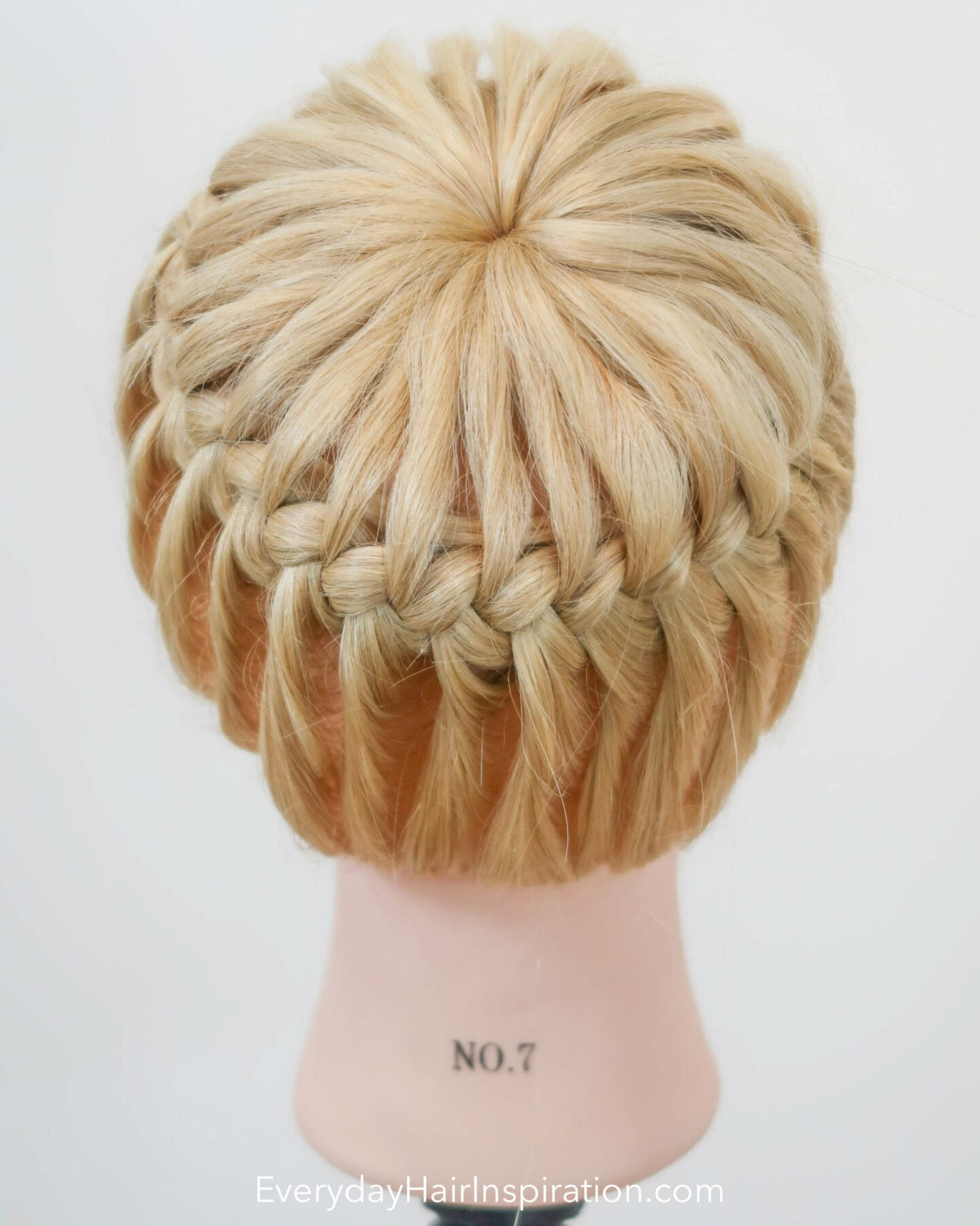 Blonde hairdresser doll seen from the back with a crown braid, braided in the hair.