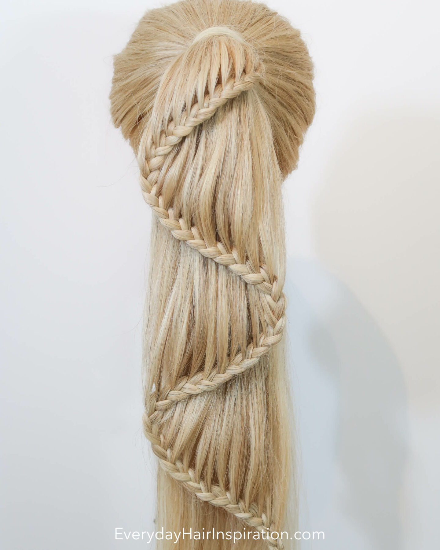 Blonde hairdresser doll seen from the back with a high ponytail with a braid in the hair. The braid is curving like an "s" shape down the hair. 