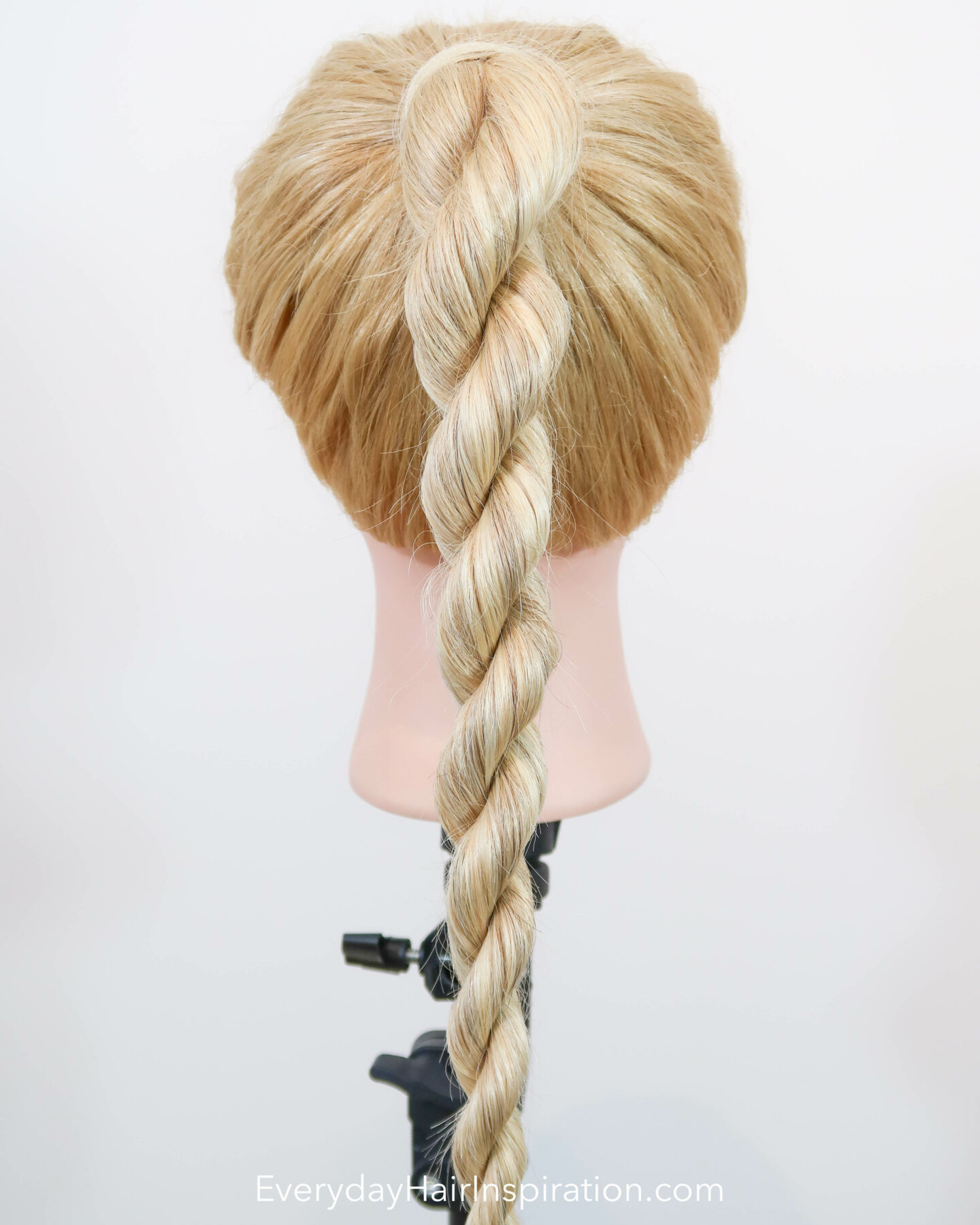 Blonde hairdresser doll seen from the back with a high ponytail with a rope braid, braided in the hair. 