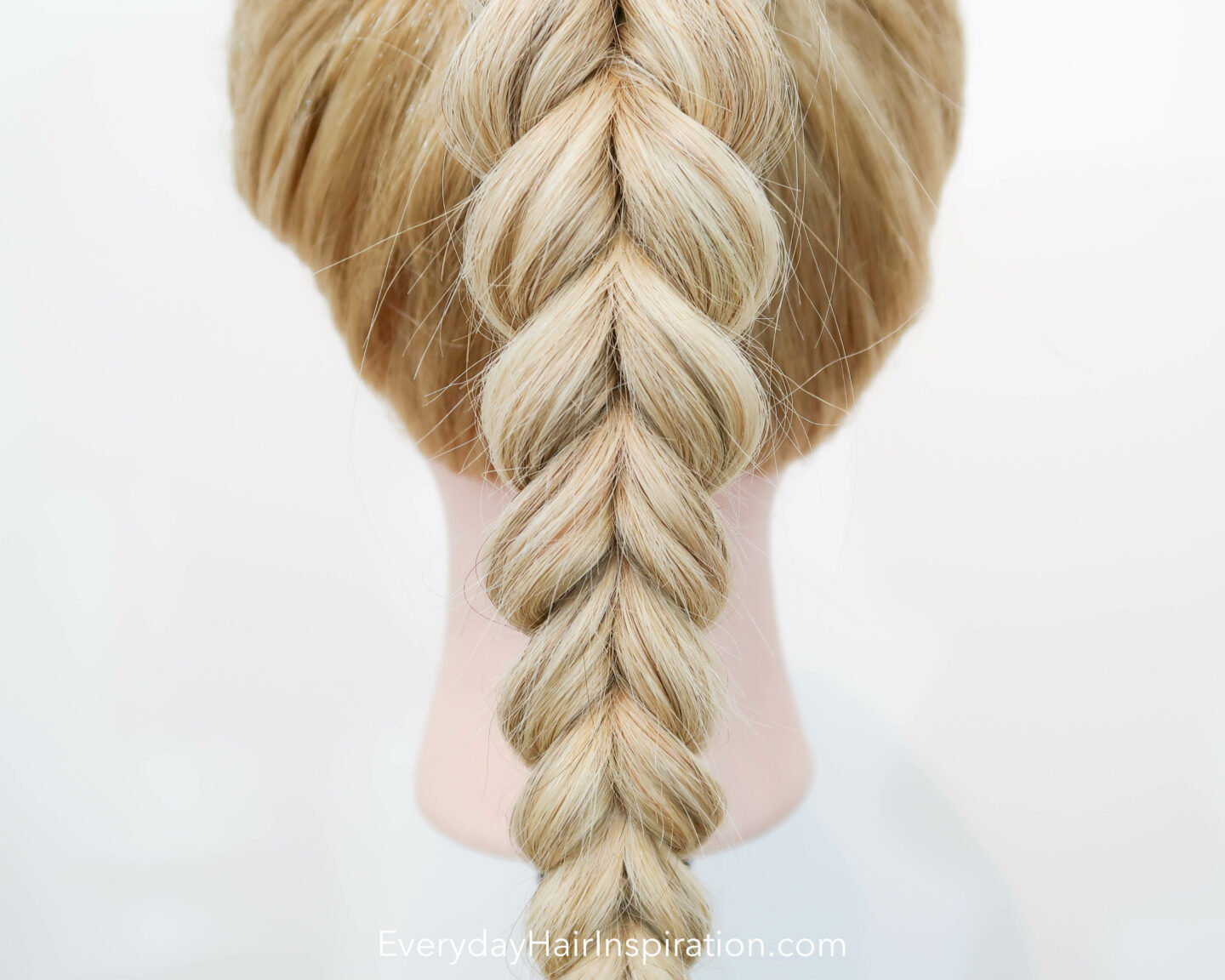 Blonde hairdresser doll seen from the back, close up, with a pull through braid in a high ponytail. 