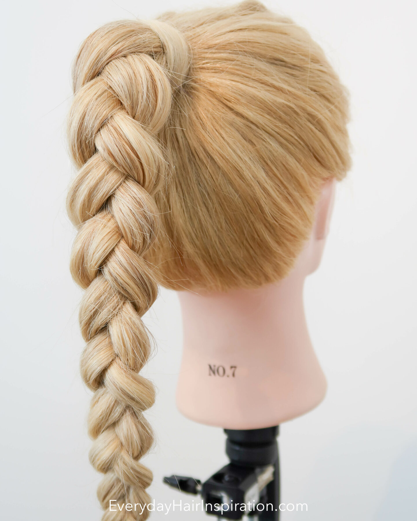 Blonde hairdresser doll seen from the back at an angle, with a high ponytail in the hair, with a 3 strand braid, made out of elastics and no braiding.