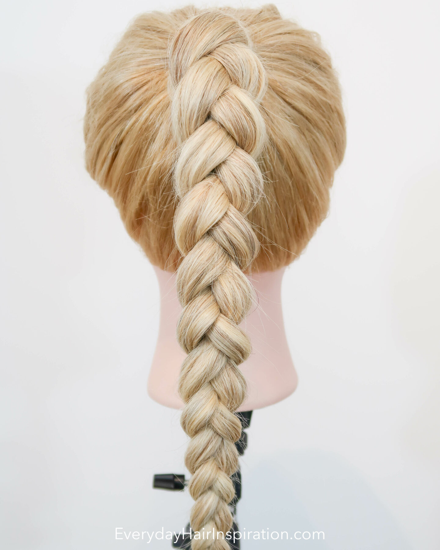 Blonde hairdresser doll seen from the back, with a high ponytail in the hair, with a 3 strand braid, made out of elastics and no braiding.