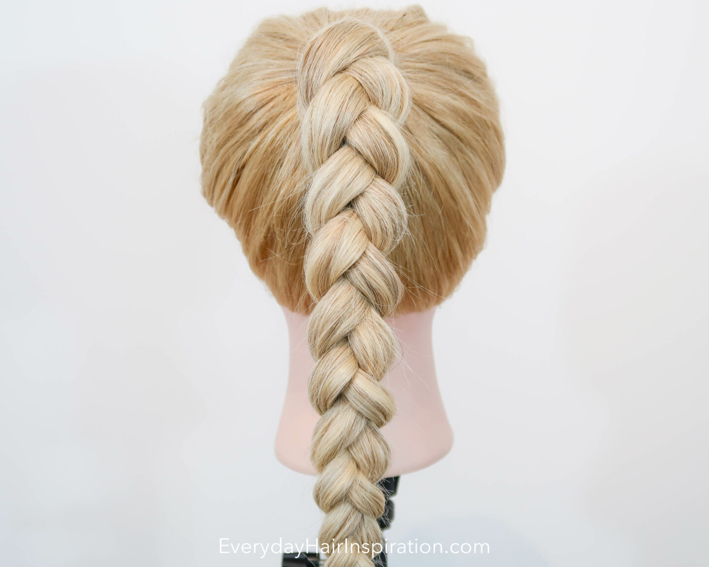 Blonde hairdresser doll seen from the back, with a high ponytail in the hair, with a 3 strand braid, made out of elastics and no braiding.