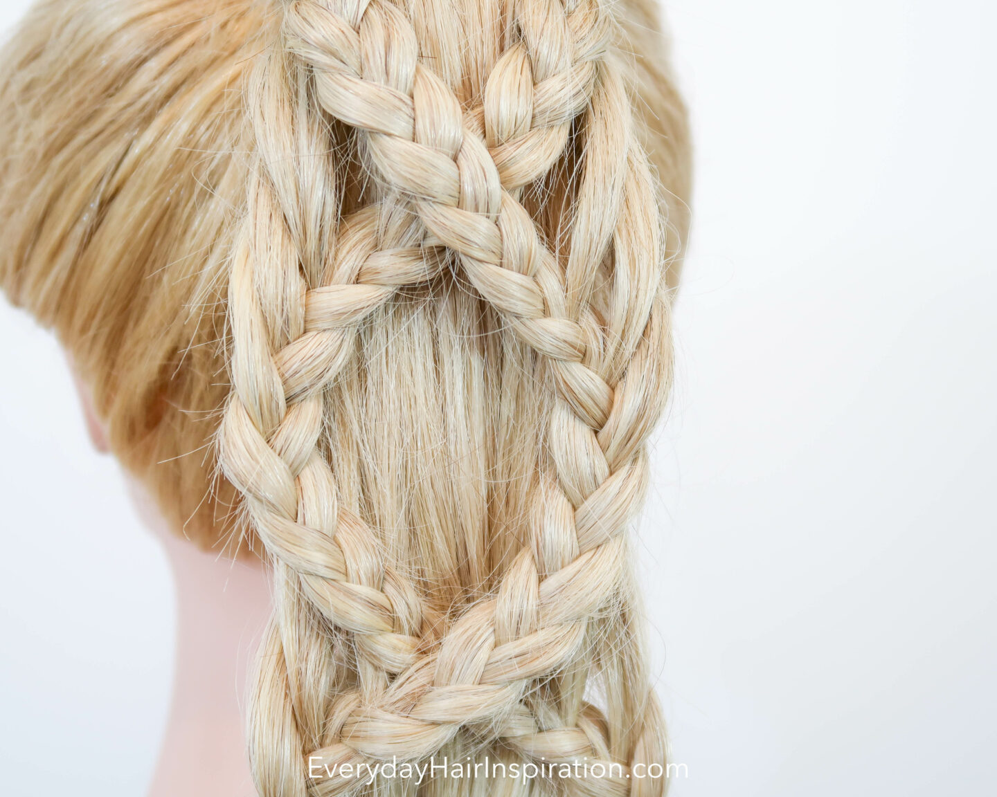 Blonde hair dresser doll seen dorm the back, close up, with a criss-cross braided ponytail.