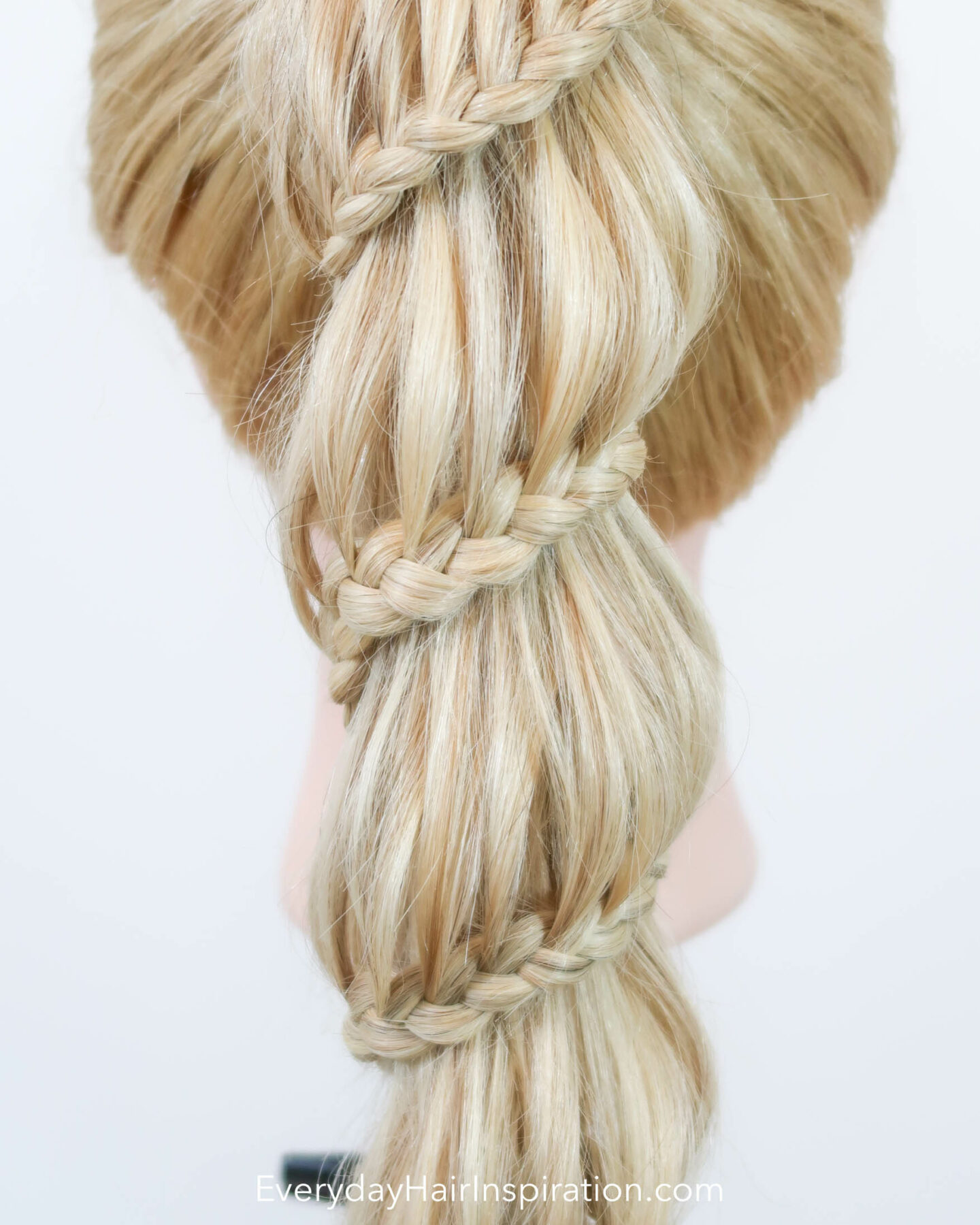 Blonde hairdresser doll seen from the back with a high ponytail. The ponytail is braided into a spiral braid, the wraps around the ponytail all the way down. Closeup of the braid.