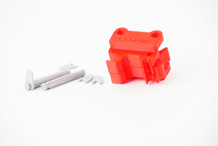 Quick coupler for the VOLVO EC160E (1:16) excavator lying on its side with associated bolts