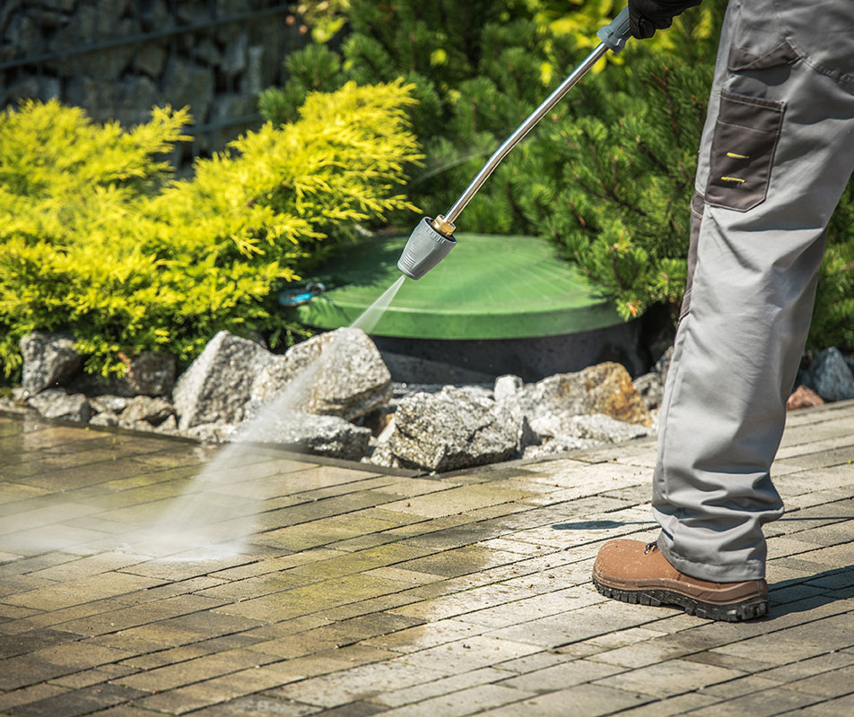 man washing his patio in the garden