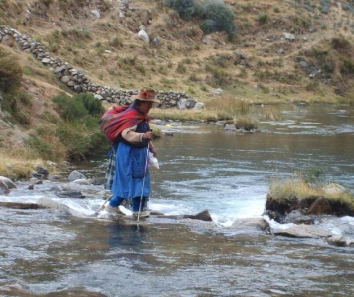 Local woman crossing river in Huaraz