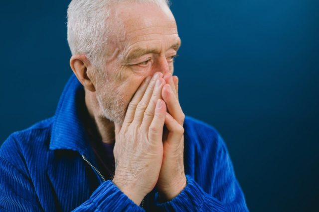 Stressed elderly man covering mouth