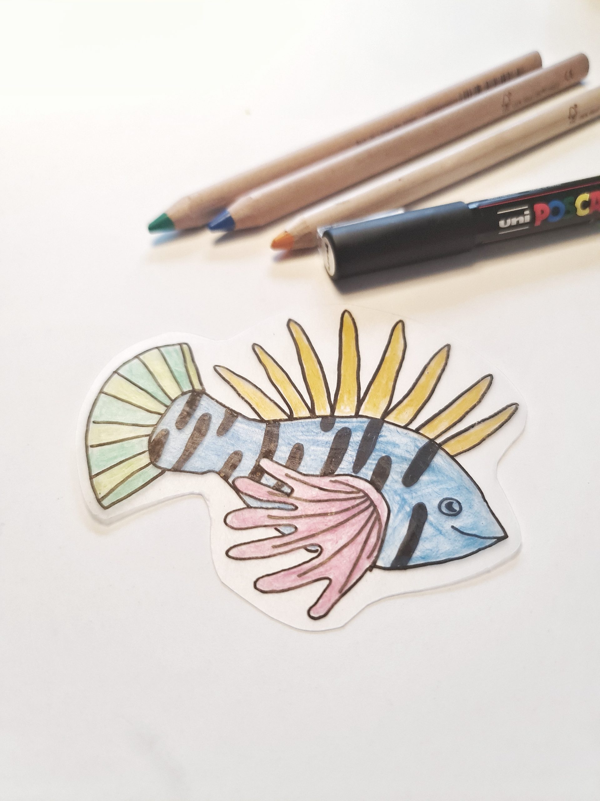 Fisk tegnet på krympeplastik med farveblyanter, tusch og skabelon fra kreakassen til børn.