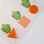 Legeunderlag til modellervoks med gulerødder i forskellige former. Modellervoksen kan formes på den måde.