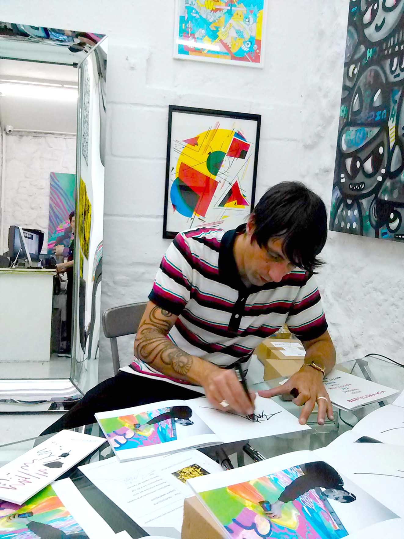 FASIM FIRMANDO CATÁLOGOS EN LA SALA INTERIOR DE LA GALERÍA baja