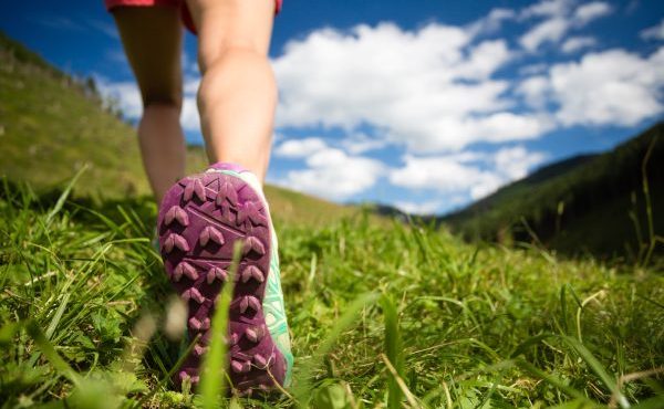 Woman walking in mountains in sport hiking shoes. Jogging trekking or training outside in summer nature inspiring motivational health and fitness concept.